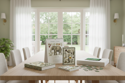 LeBonJournal hardcover botanical journals, vintage natural history calendar, heritage fruits mini book and Monet puzzle on a modern wooden dining table — gifts just arrived