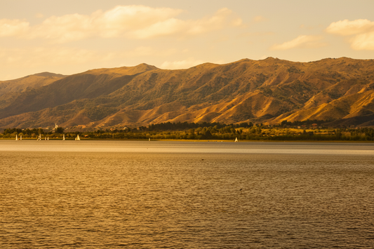 Sierras de Córdoba at golden hour with lake and sailboats in the foreground, rolling hills and native vegetation