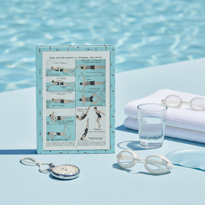 Four Picture-Lessons 1940s-1950s swimming journal standing upright on poolside surface with vintage stopwatch goggles and towel in mid-century swim club setting - LeBonJournal